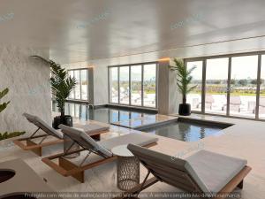 a living room with a swimming pool and chairs and windows at BeachFront Apartment - 4 pax - swimming pool in Armação de Pêra