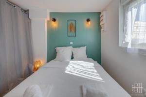 - une chambre avec un lit blanc et un mur bleu dans l'établissement La Halte 2, à Veigné