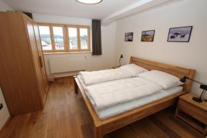 a bedroom with a bed with white sheets and a window at Helly - Kvilda - apartmány in Kvilda