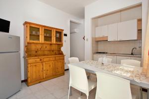 cocina con mesa, sillas y nevera en Residenza Valcris, en Lignano Sabbiadoro