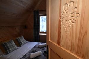 een slaapkamer met een bed in een houten hut bij Domek pod Jaworem z balią in Witów