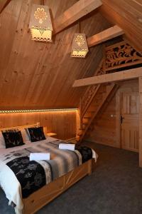 een slaapkamer met een bed op een houten zolder bij Domek pod Jaworem z balią in Witów