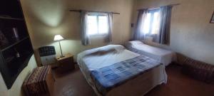 a small bedroom with two beds and two windows at La Martina. in Tunuyán