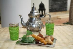 a table with a plate of food and a tea kettle at Riad Yamcha in Meknès