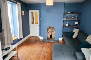 a blue living room with a couch and a fireplace at Quaint 3 bedroom Devon cottage in Honiton