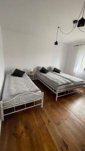 two beds in a white room with wooden floors at Sielanka Roztocze in Pary