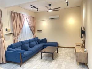a living room with a blue couch and a table at Peach Villa @ Putatan in Kota Kinabalu