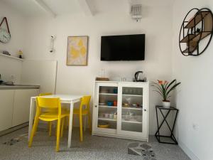 a kitchen with a table and yellow chairs and a tv at 8+8 Appartamento con garage in Livorno