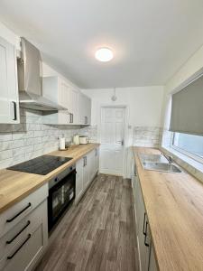 a kitchen with white cabinets and a wooden counter top at NEW Unique 4 Bed Families Contractors 靠近唐人街 in Nottingham