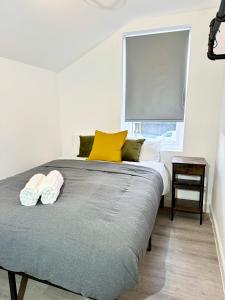 a bedroom with a bed with yellow pillows and a window at NEW Unique 4 Bed Families Contractors 靠近唐人街 in Nottingham