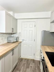 a kitchen with white cabinets and a white door at NEW Unique 4 Bed Families Contractors 靠近唐人街 in Nottingham
