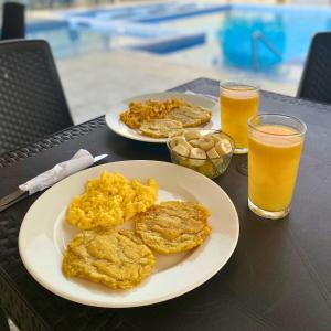 a table with two plates of food and two glasses of orange juice at Cabañas covemar in Coveñas