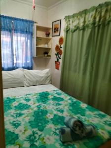 - une chambre avec un lit et une couverture fleurie dans l'établissement Cronin Residence Inn, à Oslob