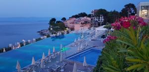 a pool with chairs and umbrellas next to the water at BELLAVISTA apartman Punta in Veli Lošinj