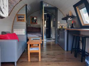 a tiny house with a couch and a table at Riverside Pod, West Highland Way Holidays in Kinlochleven