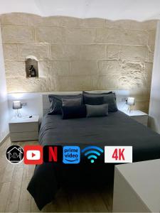1 dormitorio con 1 cama con pared de piedra en SASSARI-CENTRO Elegante Appartamento con WiFi e Netflix, en Sassari