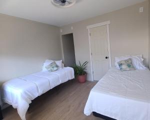 two beds in a room with white walls at Hotel on Magnolia East 'HOME' in Wildwood