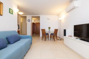 a living room with a blue couch and a table at BELLAVISTA apartman Punta in Veli Lošinj