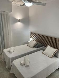Cette chambre blanche comprend 2 lits avec des draps et des oreillers blancs. dans l'établissement Apartamentos Costa Blanca, à Playa de Gandia