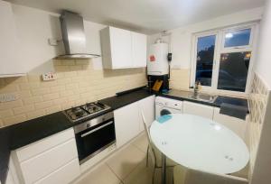 a white kitchen with a table and a sink at Double Room near Canary Wharf 28 in London