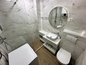 ein Badezimmer mit einem WC, einem Waschbecken und einem Spiegel in der Unterkunft Apartments 28 in Podgorica