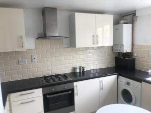 a kitchen with white cabinets and a stove top oven at Double Room near Canary Wharf 32 in London