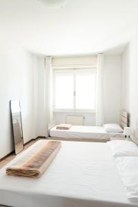 ein weißes Schlafzimmer mit 2 Betten und einem Fenster in der Unterkunft 54 Bilocale con ampio Terrazzo a 50 metri dal mare in Lignano Sabbiadoro
