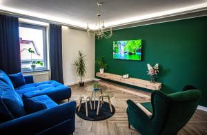 a living room with blue furniture and a green wall at Apartament „Nad Ratuszem” in Częstochowa