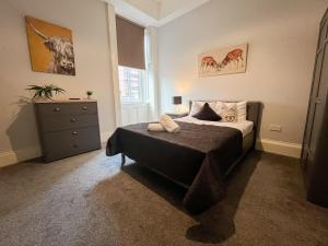 a bedroom with a bed and a dresser in it at City Centre 5 Bedroom Flat on Sauchiehall Street in Glasgow