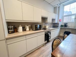 cocina con armarios blancos y mesa de madera en City Centre 5 Bedroom Flat on Sauchiehall Street en Glasgow