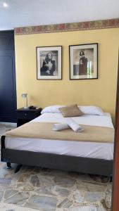 a bed in a bedroom with two pictures on the wall at Hotel Montecarlo in Cali