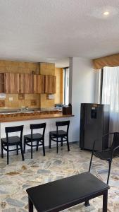 a kitchen with four chairs and a table and a refrigerator at Hotel Montecarlo in Cali +65 photos