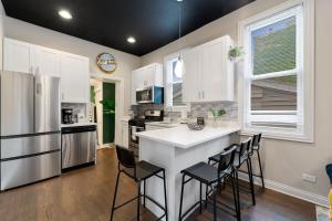 a kitchen with a white counter and chairs in it at Stylish 2 BDR Coach House Steps From The Lake in Chicago