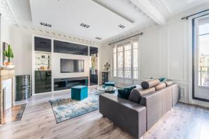 een woonkamer met een bank en een tv bij luxueux appartement haussmannien in Saint-Mandé