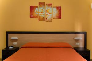 a bedroom with a bed with three paintings on the wall at Albergo San Lorenzo in Grosseto