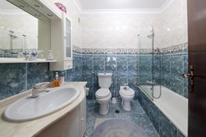 uma casa de banho com um lavatório, um WC e um chuveiro em Quartos da Tia Laura na Nazaré