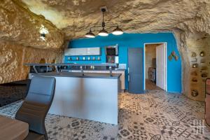 eine Küche mit blauen Wänden und einer Steinmauer in der Unterkunft La Troglo - Maison typique de notre région in Vouvray + 18 Fotos