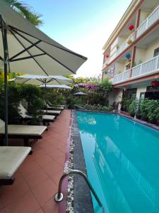 einen Pool mit Tischen und Sonnenschirmen neben einem Hotel in der Unterkunft Phuc Thao Villa in Hoi An