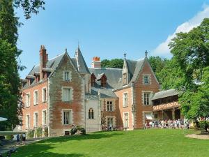 a large brick building with people standing in the yard at La Troglo - Maison typique de notre région in Vouvray