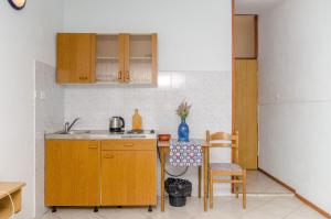 eine Küche mit Holzschränken, einer Spüle und einem Tisch in der Unterkunft Studio Apartments Klara and Rio in Stomorska