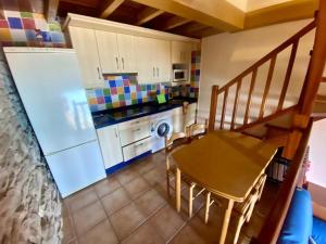 a small kitchen with a table and a dining room at El balcón del Escanu. in Lastres