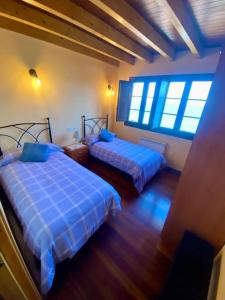 two beds in a room with blue sheets at El balcón del Escanu in Lastres
