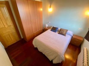 1 dormitorio con cama blanca y suelo de madera en El balcón del Escanu, en Lastres
