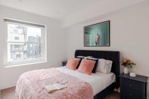 een slaapkamer met een bed met een roze deken en een raam bij Frankie Says - London lodgings don't get more fabulous than the Fitz n' Glamour, a dazzling 1 BR apartment in central Fitzrovia in Londen