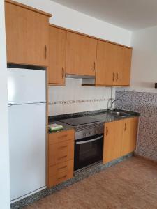 a kitchen with wooden cabinets and a stove and a refrigerator at Piso da Charca in Fisterra