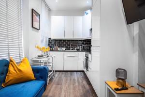 uma sala de estar com um sofá azul e uma cozinha em Livestay-Charming London Retreat Stylish 1BR near Kings Cross&Farrington em Londres