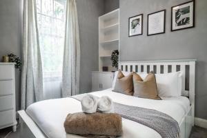um quarto com uma cama branca e 2 toalhas num banco em Livestay-Charming London Retreat Stylish 1BR near Kings Cross&Farrington em Londres