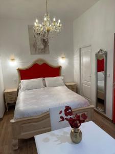 een slaapkamer met een bed met een rood hoofdeinde en een tafel bij Petit studio presbytère dans L'Église in Narbonne