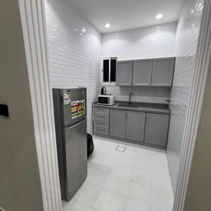 a small kitchen with a refrigerator and a sink at شقة فاخرة بغرفة نوم وصالة 10 Luxury APT in Riyadh