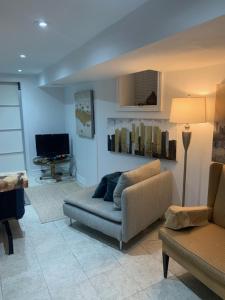 a living room with a couch and a chair at Cosy comfortable basement apartment. in Toronto